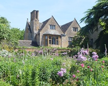 Older stone building, set in a field of green and purple flowers