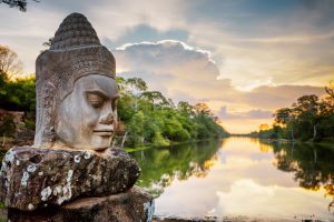 Ruins of a stone statue of a head, near tropical forest