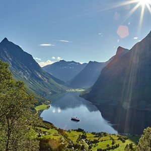 Expedition ship in a lake surrounded by lush green fjords